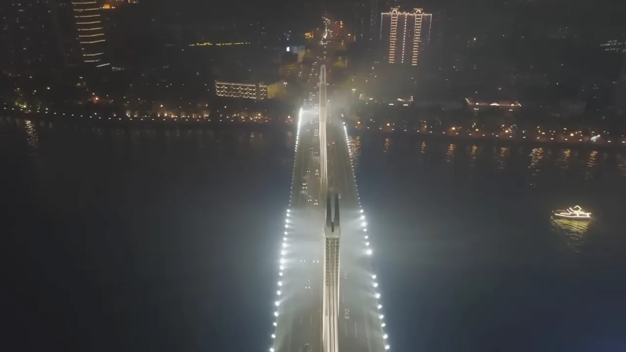 Aerial night view of a major bridge and cargo shipping lanes over open water