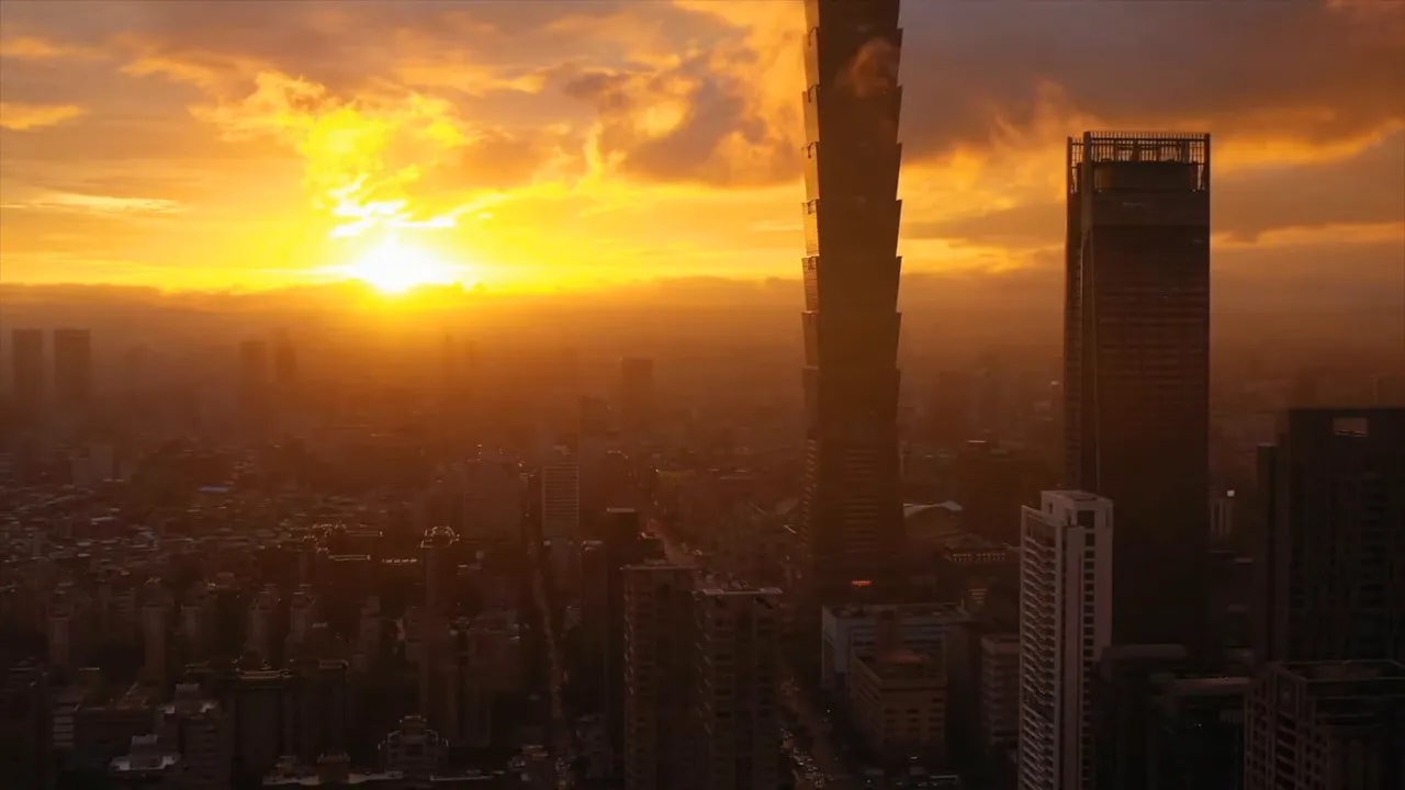 Wide city skyline at sunset with tall towers and haze