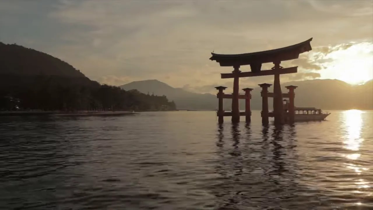 Sunset over a calm river with a traditional gate-like structure on stilts