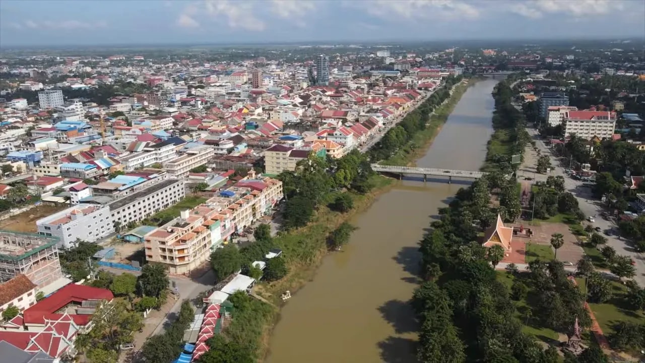 Wide aerial view of a Cambodian city with a river running past buildings