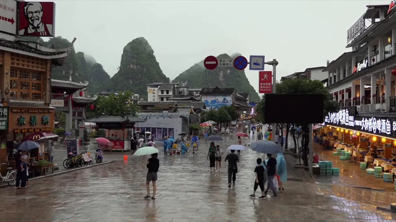 Wide view of rainy crowds in a traditional Chinese town during Qingming