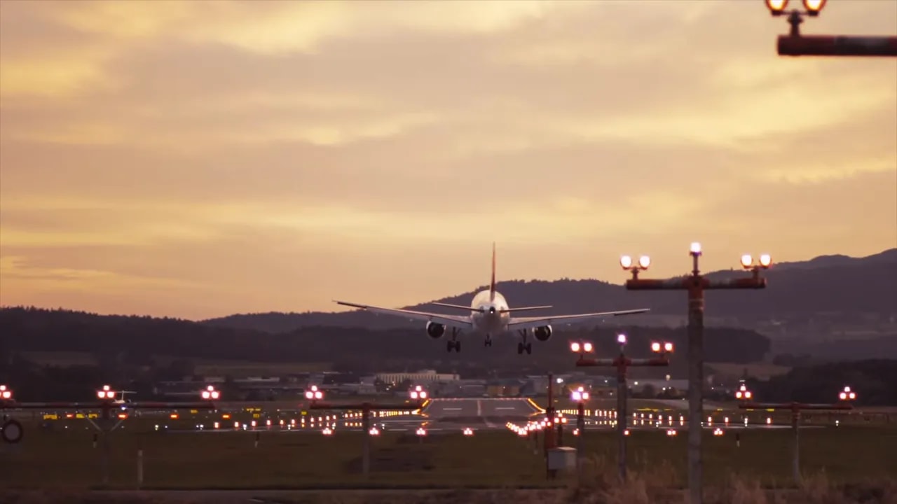 Passenger jet landing at an airport at sunset